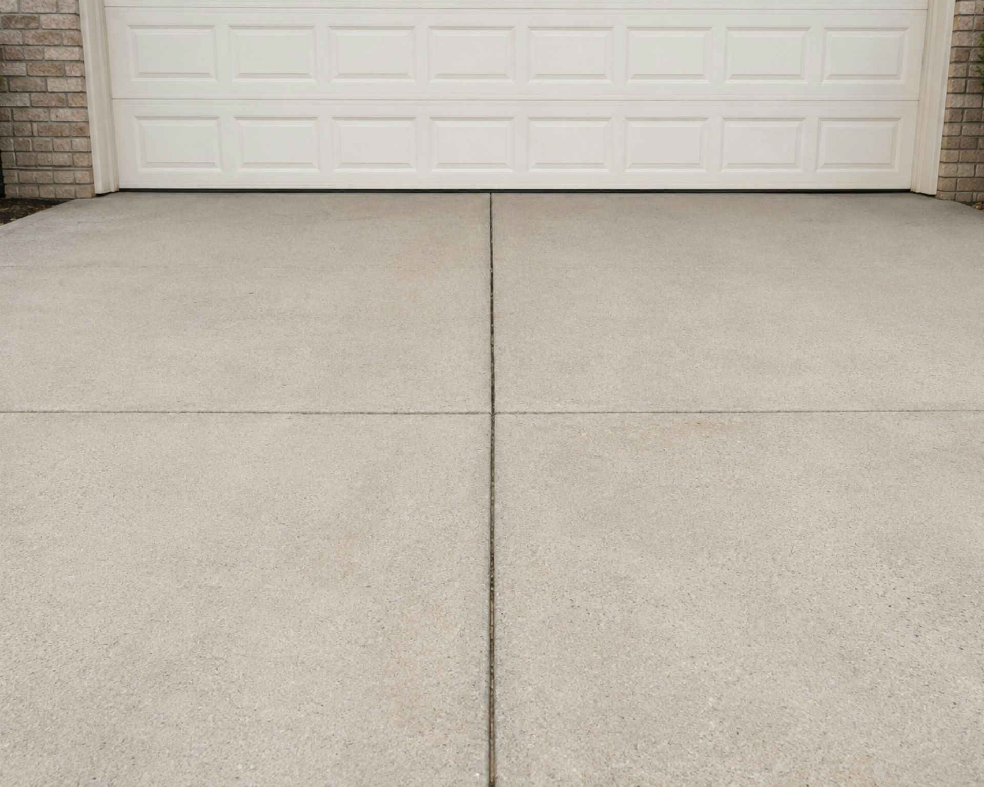 A concrete driveway in front of a white garage door